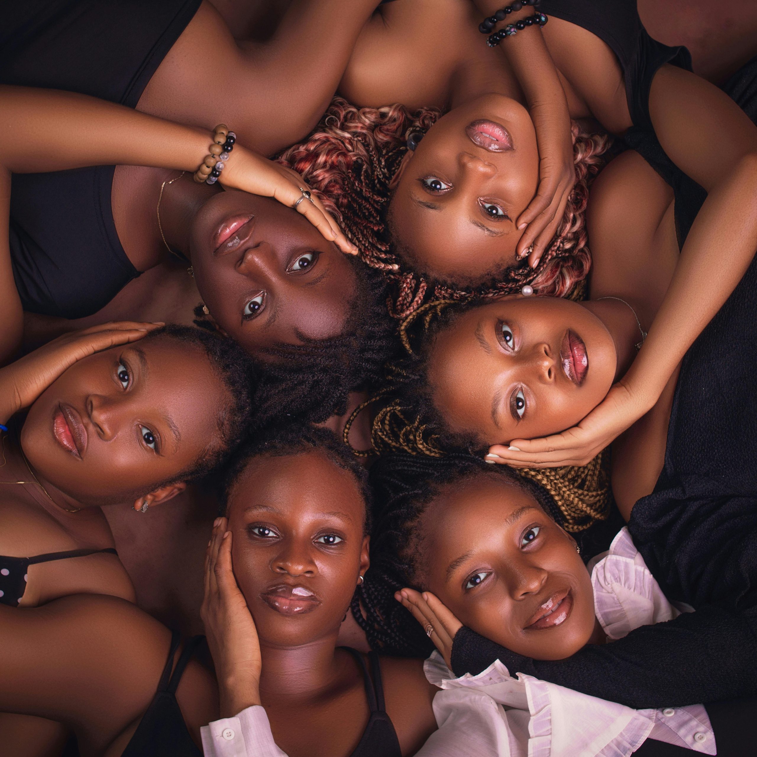 Home A captivating aerial shot of six diverse women lying together, exuding unity and elegance.
