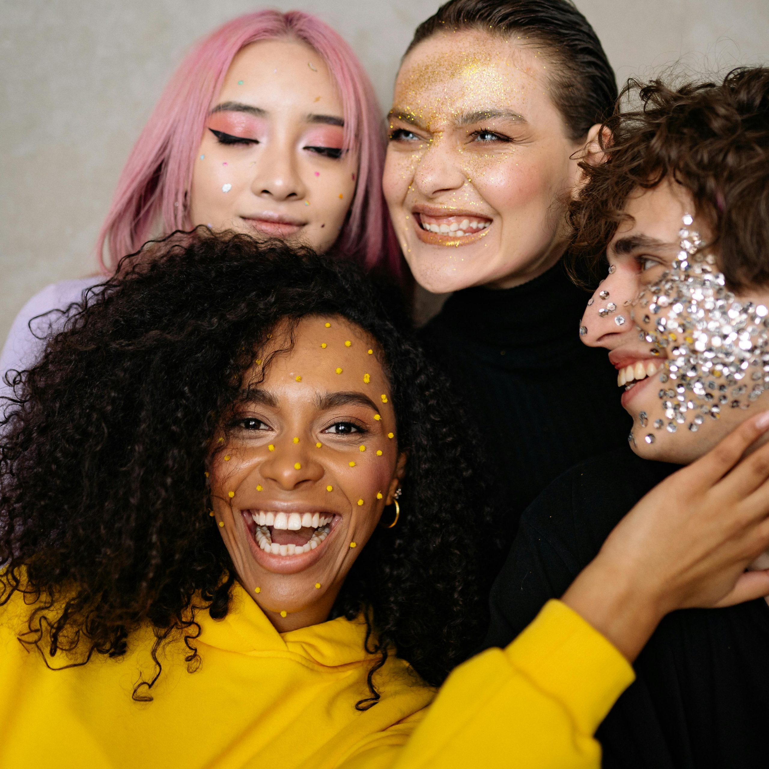 Home Joyful group of Gen Z friends with colorful glitter makeup, celebrating diversity and style in a close-up studio portrait.