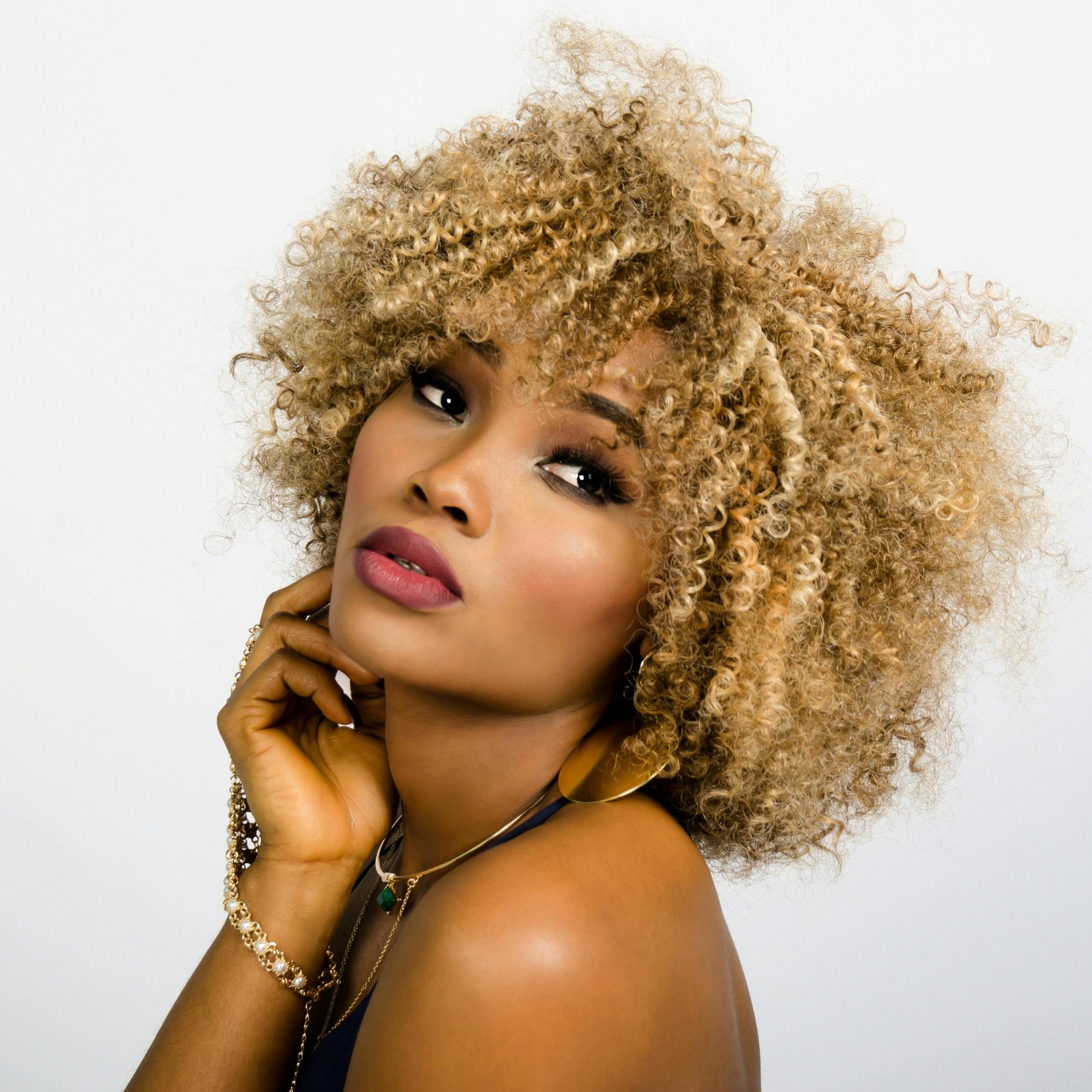 Home Elegant portrait of a woman with golden curly hair, showcasing beauty and confidence.